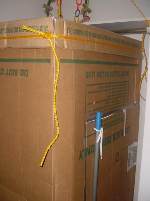 This is the right side of the box if looking at the previous picture. This picture shows the door into the grow box. It warped so I tied a broom handle to the door with shoelaces to straighten it back out. The yellow rope was used to tie the roof back onto the box after the box was cut shorter for height requirements.